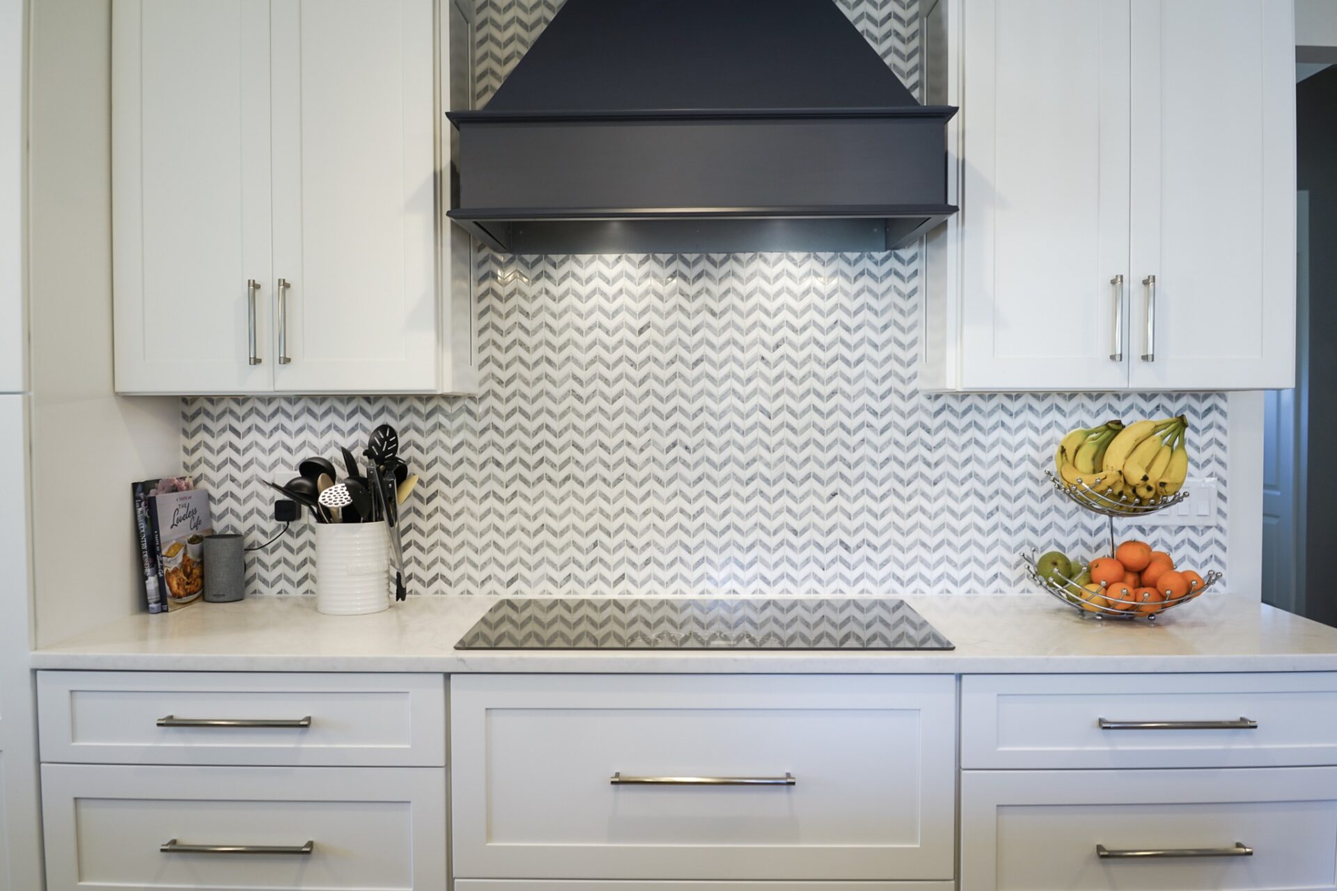 berlin Kitchen Remdel Contemporary kitchen remodel in Berlin, CT featuring white shaker cabinets, chevron tile backsplash, and a sleek black range hood.